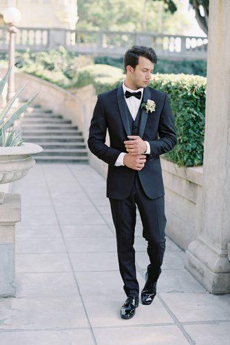 besame wedding styled shoot groom with a butterfly in a black suit with a waistcoat in black lackered leather shoes and a buttonhole of roses carrie king photographer