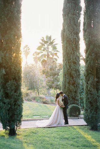 besame wedding styled shoot bride in a dress with a train and the groom among the tall cypress trees carrie king photographer
