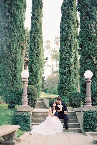 besame wedding styled shoot bride in a dress with a train and the groom in front of sitting on a stone stairs carrie king photographer