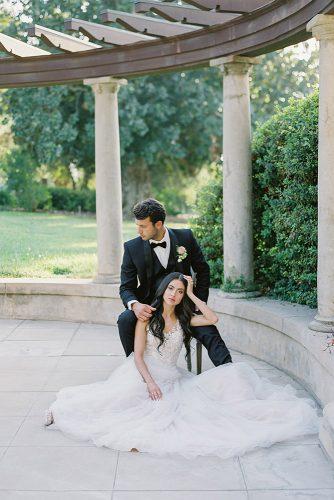 besame wedding styled shoot romantic photography bride with dark loose curls and groom with boutonniere sit near the columns carrie king photographer