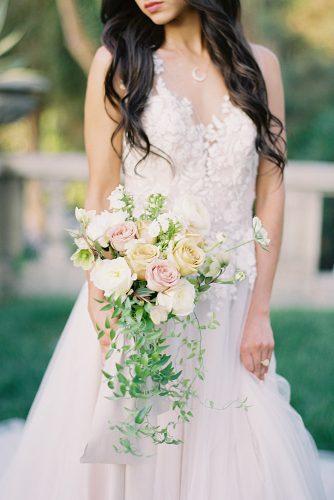 besame wedding styled shoot bride in lace dress holding a cascading bouquet with peach black pink roses and greenery carrie king photographer