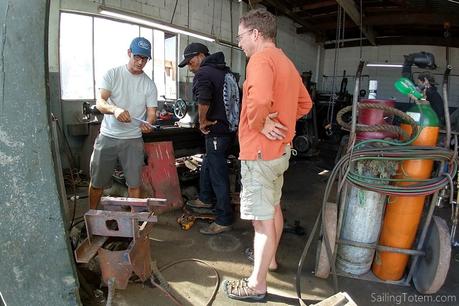 Three men confer inside a well used machine shop