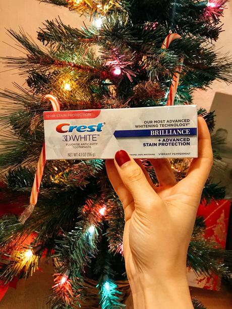 a box of crest 3d whitening toothpaste - it's a fancy holographic post that flashes pretty colors when moved about. the box is held up in front of a mini Christmas tree.  