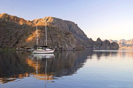 sailboat at anchor next to stunningly rugged desert coastline in Baja