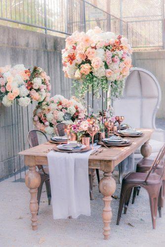 spring wedding decor tall flower centerpiece with roses and greenery on wooden table manda weaver photography