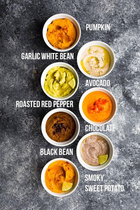 overhead view of 7 hummus recipe flavors in white ramekins