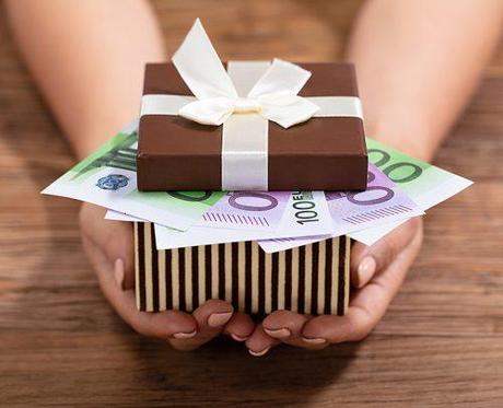 how much to spend on a wedding gift hands holding cash in gift box
