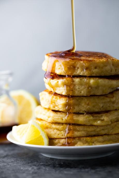 side view of a stack of lemon ricotta pancakes with syrup drizzling over
