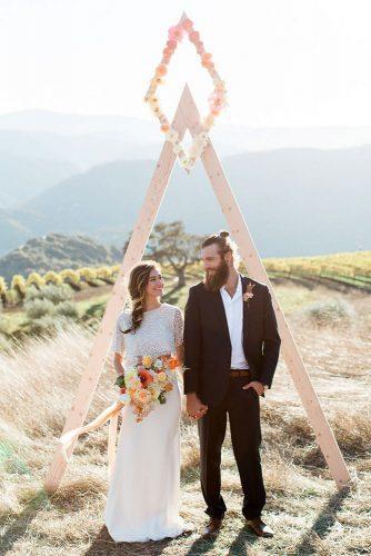 minimalist wedding decor wooden triangle arch with pink flowers carlie statsky