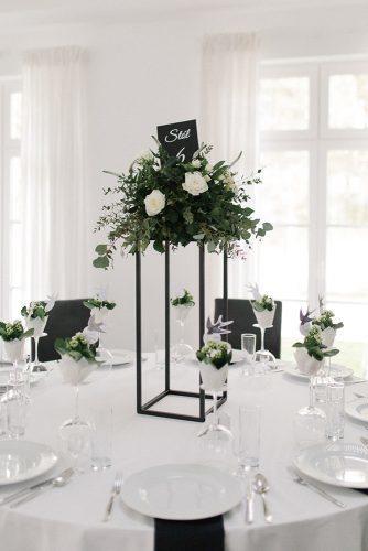 minimalist wedding decor centerpiece tall with greenery and white roses on round table anna dymek