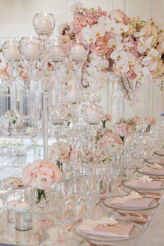 modern wedding decor ideas gentle pink flowers and white orchids in tall centerpieces on table with candles samuellippkestudios
