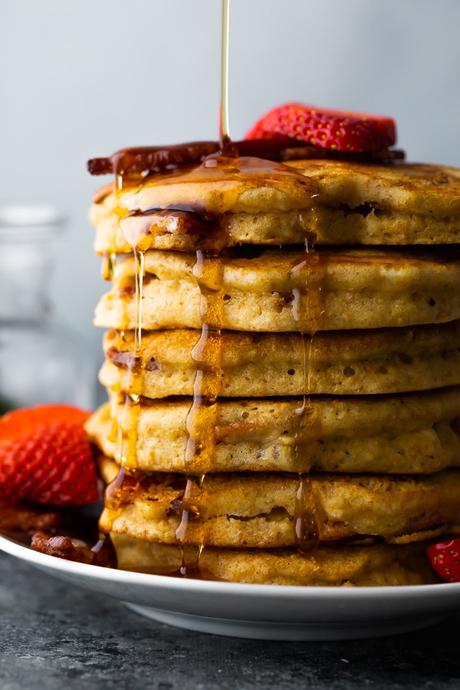 maple syrup drizzling on a stack of bacon pancakes