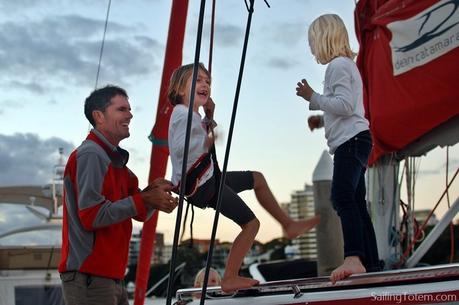 Two little girls in climbing harnesses play by swinging in sailboat rigging