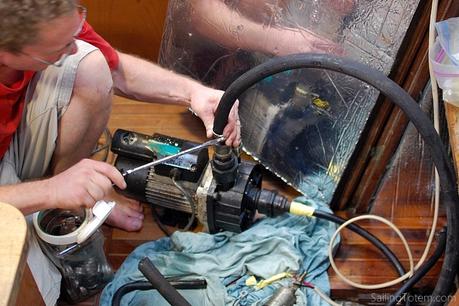 man using diesel transfer pump below deck on sailboat