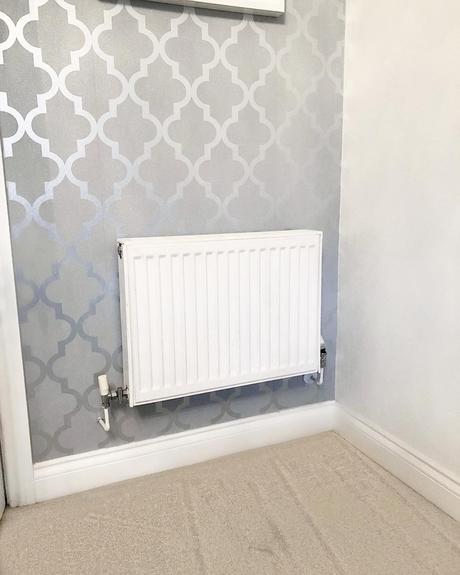 A white convector radiator on a gray wall.