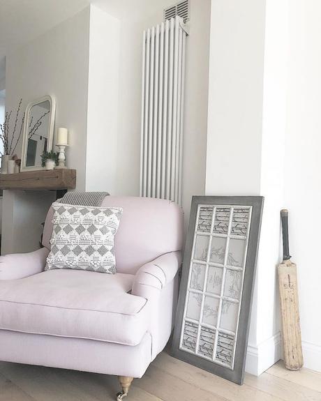 a vertical Milano Windsor column radiator in white behind a pink arm chair