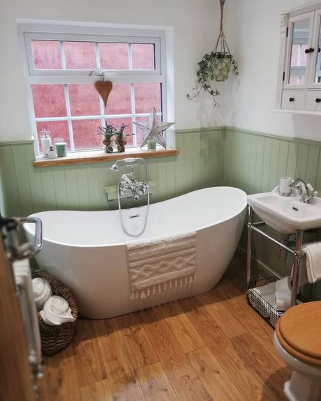 a freestanding bath in a green and white bathroom