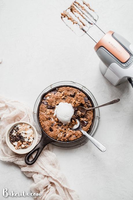 This Magic Chocolate Chip Skillet Cookie is a big, gooey and decadent gluten-free and vegan dessert. With chocolate, walnuts, and coconut, it's reminiscent of my longtime favorite, magic cookie bars. It's best topped with ice cream and so easy to make.