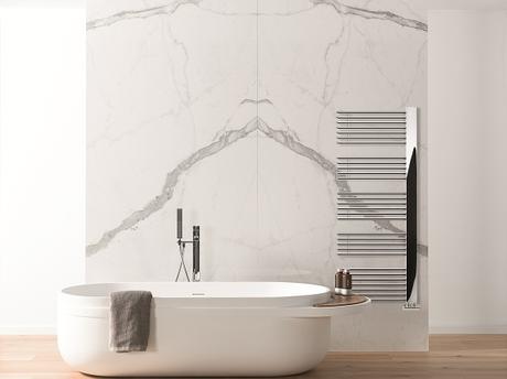 The Lazzarini Way Grado heated towel rail on a marble wall in a bathroom with a freestanding bathtub