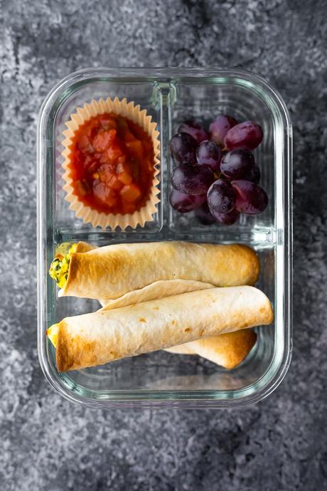 breakfast taquitos in meal prep container with eggs and salsa