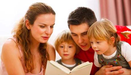 Parents reading to their two young children.