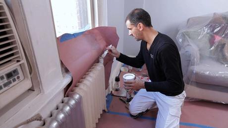 A man applying primer to a radiator before painting it in full