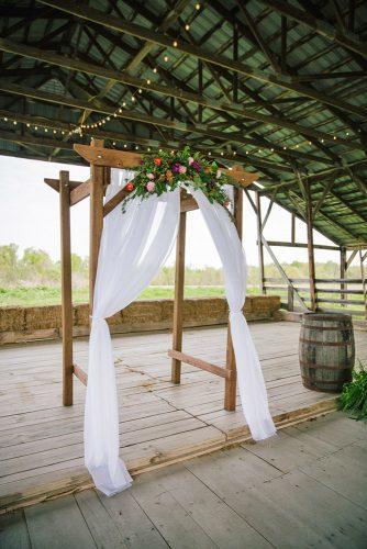 rustic wedding ideas wooden arch decorated with roses and flying white cloth heather todd photography