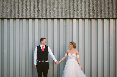 Summer Solstice Wedding – Polly and Steve bride and groom pose against a barn