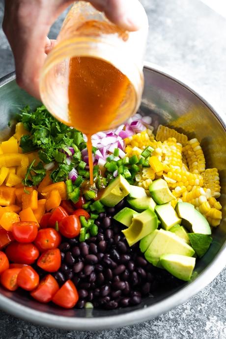 pouring dressing on black bean and corn salad