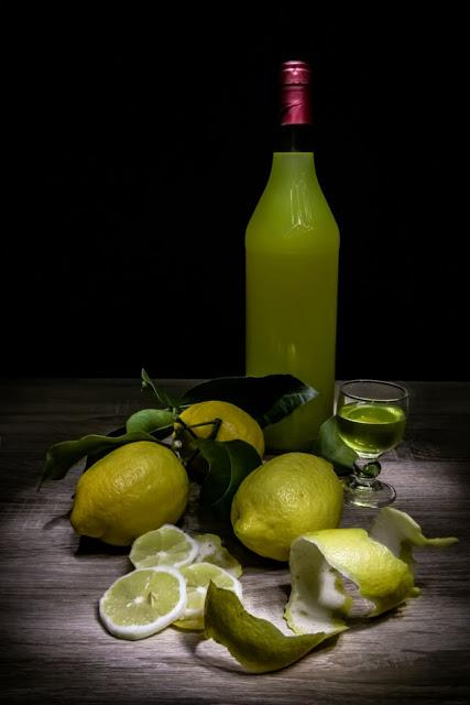 A picture of a bottle of limoncello, and lemons with the peel scattered around it