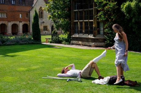 a wedding guest laying on the lawn at pembroke college wedding