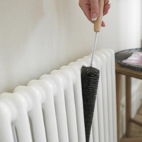person cleaning a radiator with a specialist radiator brush