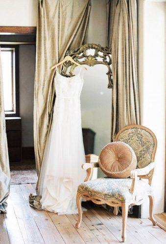 hanging wedding dress dress om mirror near chair codyhunterphotography