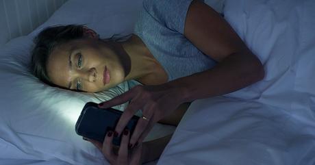 Woman lying in bed using smartphone