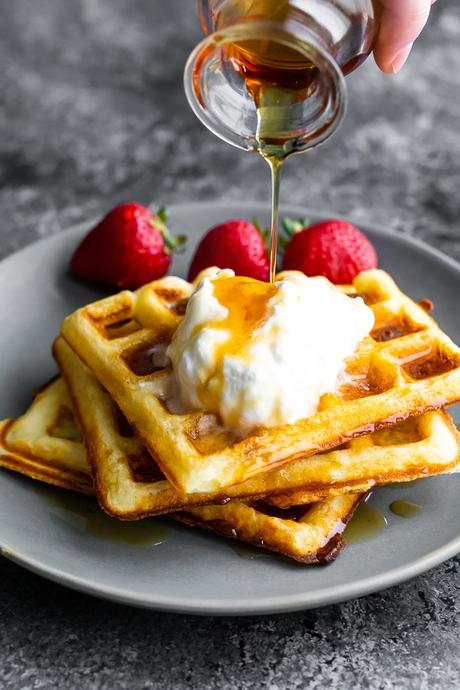 pouring syrup over the buttermilk waffles