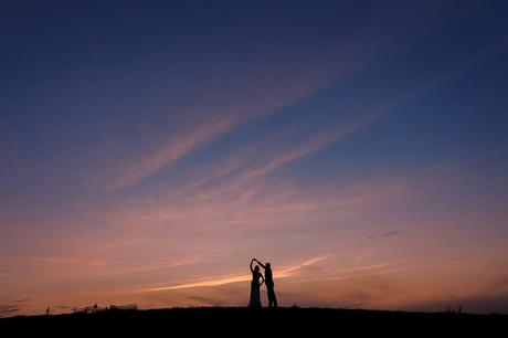 bride and groom dance in front of the sunset at a maidens barn wedding