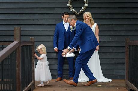 a father chases a flowergirl away from the bride and groom