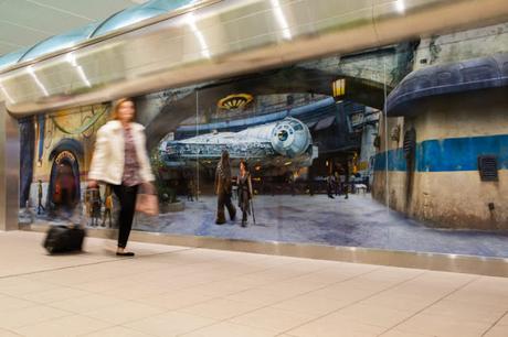 A traveler at Orlando International Airpott in Orlando, Fla., passes by a scene from Star Wars: Galaxy’s Edge at Disney’s Hollywood Studios prior to boarding a shuttle to the Main Terminal, Nov. 16, 2019. Disney installed these artistic wraps on the shuttle stations to immerse airport travelers in scenes from Star Wars: Galaxy’s Edge. 