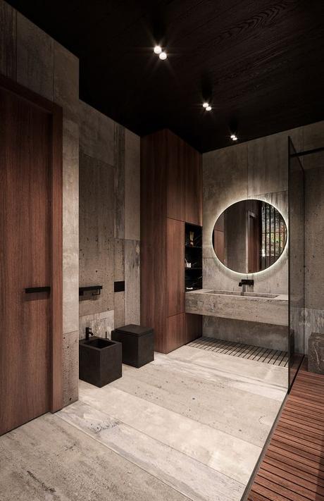 big bathroom with natural wood and concrete finishes with a concrete vanity, round mirror, and matte black sink hardware