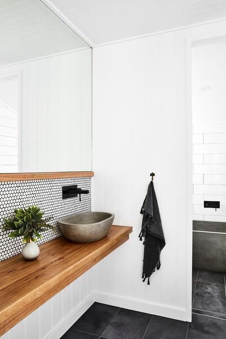 simple Scandinavian inspired modern bathroom with single sink natural wood vanity and matte black sink hardware 