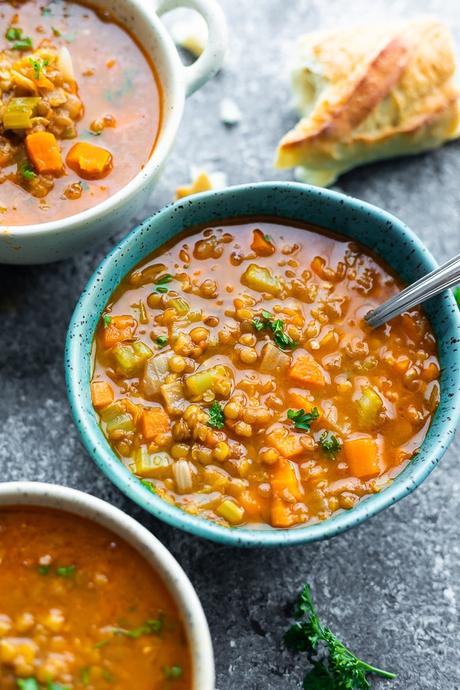 blue bowl with lentil soup and bread in background