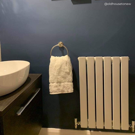 small radiator on a blue bathroom wall