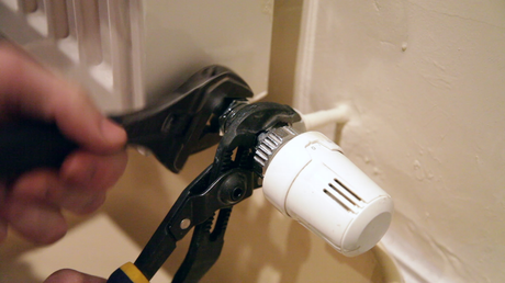 A man removing a radiator valve from a radiator