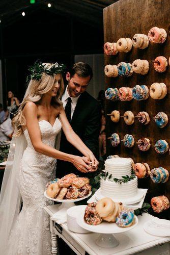 wedding dessert table ideas the groom and the bride cut the cake around the plate with donuts and on the wall donuts luke and mallory via instagram