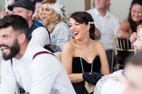 Wedding guest wearing flapper style dress and laughing during speeches. 