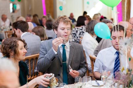 Guest at colourful wedding blows bubbles.