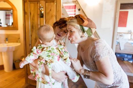 Mum and grandmother make faces to baby flower girl at wedding. 