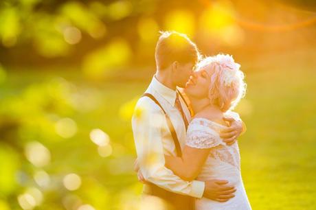 Bride in flower crown snuggles groom wearing braces in sunset golden hour at East Riddlesden Hall. 