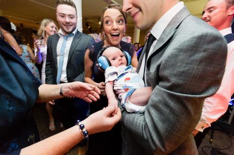 Adorable baby wearing ear defenders at London wedding. 