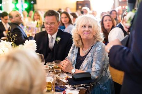 Groom's mom smiles during wedding speeches. 